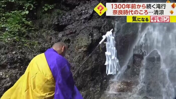 僧侶が滝に向かい頭を下げている