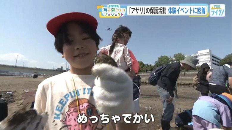 掘ったアサリをうれしそうに見せる子ども