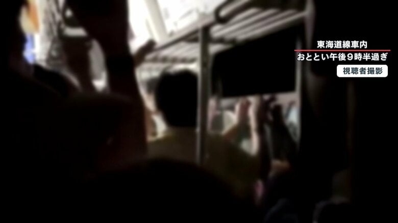 冷房の止まった車内で窓を開ける乗客