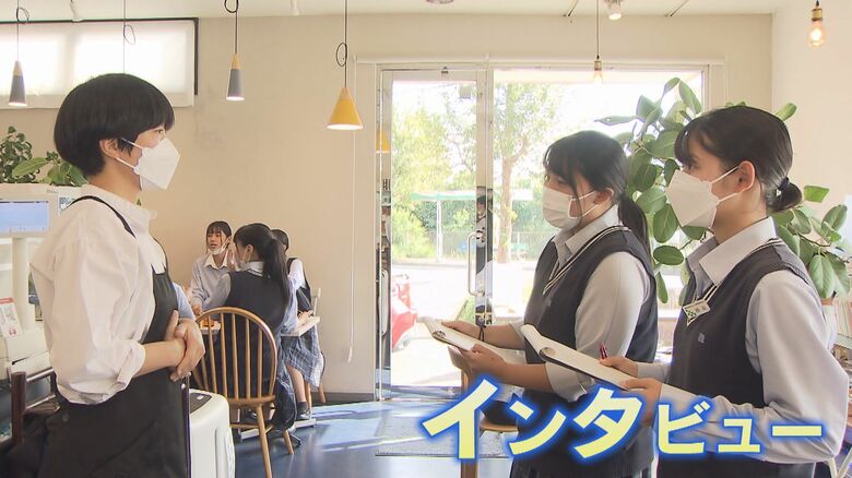 飲食店で写真撮影やインタビューを行う高校生