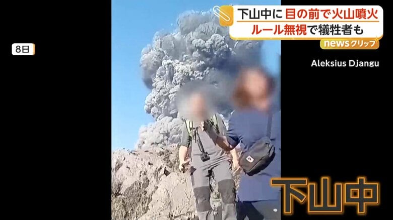 登山者の背後で立ちのぼる噴煙