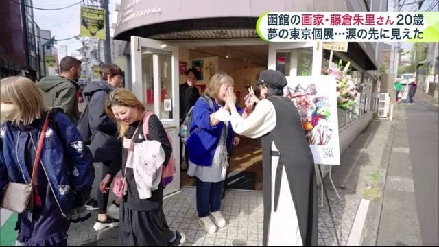 個展を満喫した来客者とハイタッチをする藤倉さん