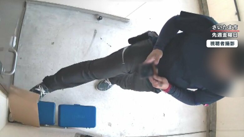 荷物を足で蹴って隙間に入れようとする
