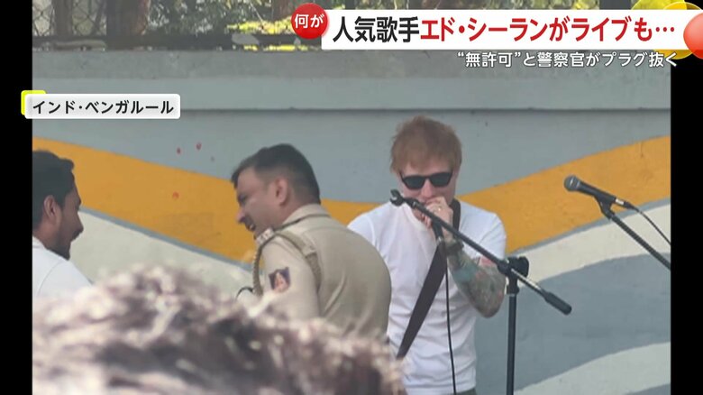 エド・シーランの前で男性と会話する警察官