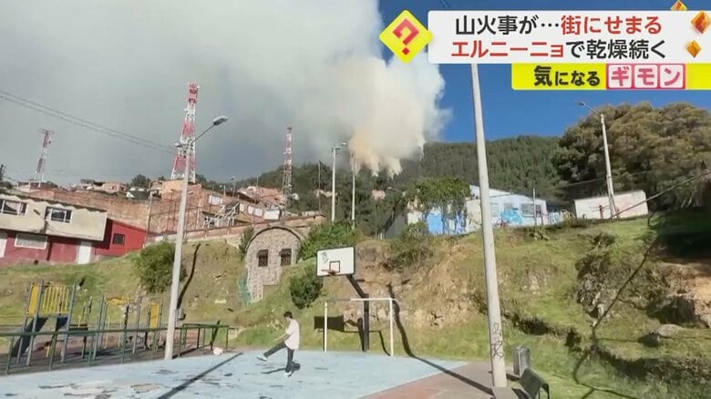 サッカーをする子どものすぐ後ろで山火事の煙が立ち上る