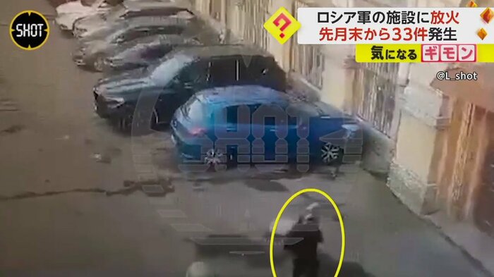 頭に何かをかぶった人物が建物の入口に近づく