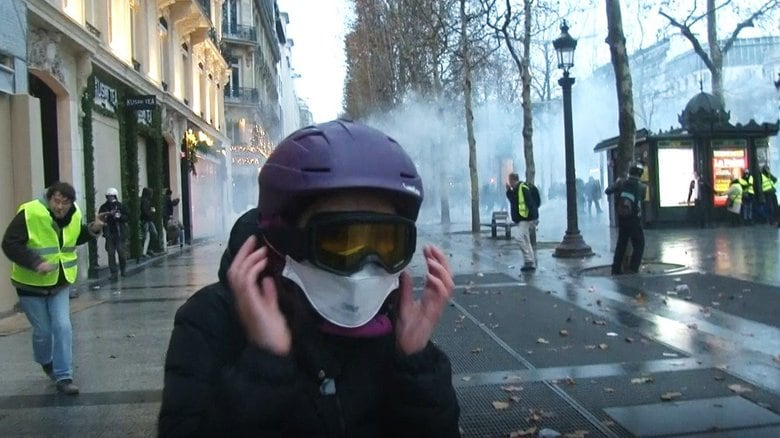 ヘルメットとゴーグルをしてデモの取材をする石井特派員