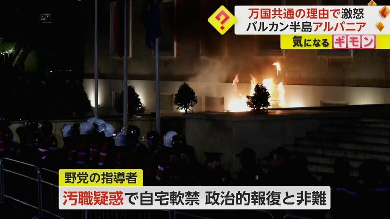 政府庁舎前を警備する警察官とその後ろで上がる巨大な火柱