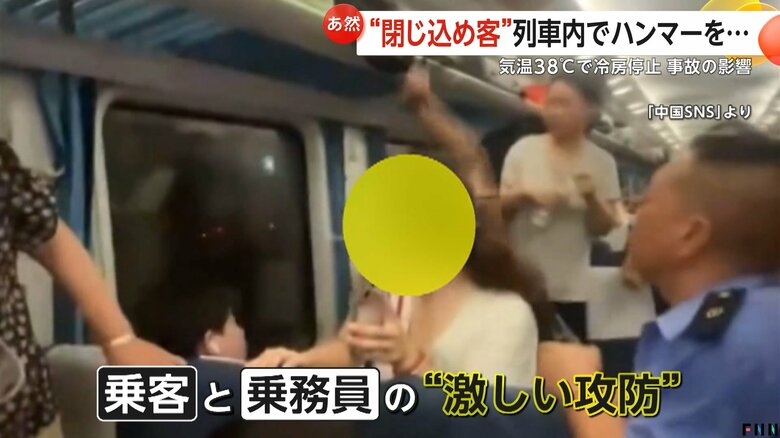 窓をハンマーでたたく乗客を静止しようとする乗務員