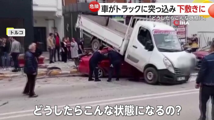 赤い車の上に折り重なるように乗っているトラック