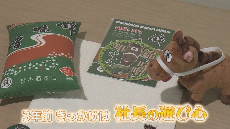 錦味噌「さとるくん」のグッズ　おひるねまくら、マグネットステッカー、ぬいぐるみが並ぶ