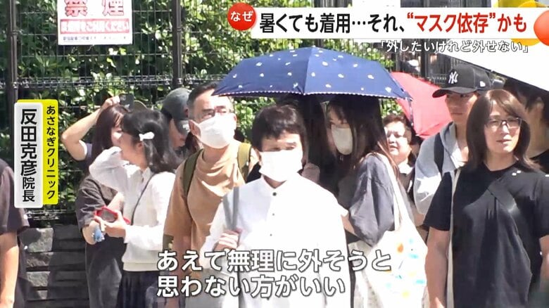 日傘を差しながらマスクをする人