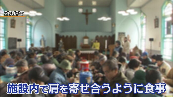 肩を寄せ合い、炊き出しの食事をとる