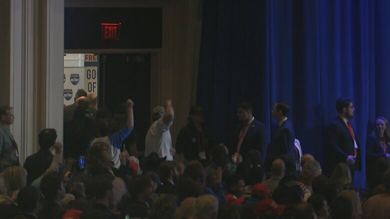 会場内で抗議する人によって演説が一時中断