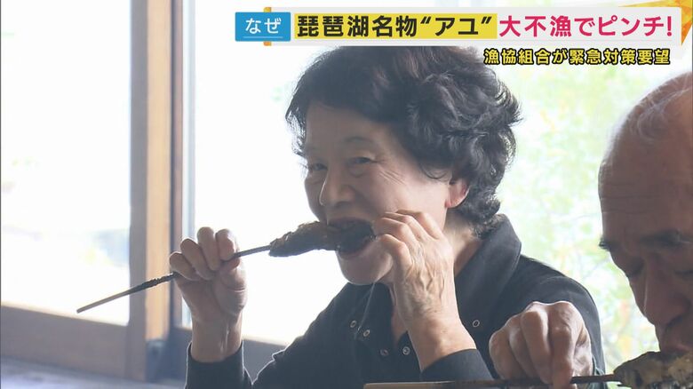 囲炉裏で焼いたアユを楽しむ客