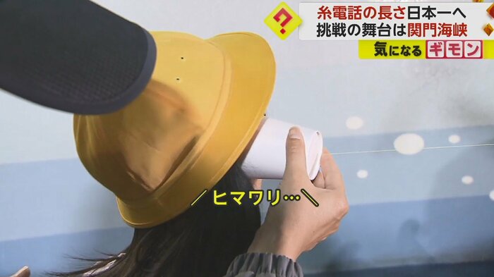 山口側の小学生。糸電話に耳をあてると、福岡側から「ヒマワリ」と聞こえた