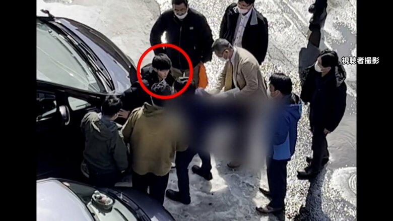 何人もの捜査員に取り囲まれた男