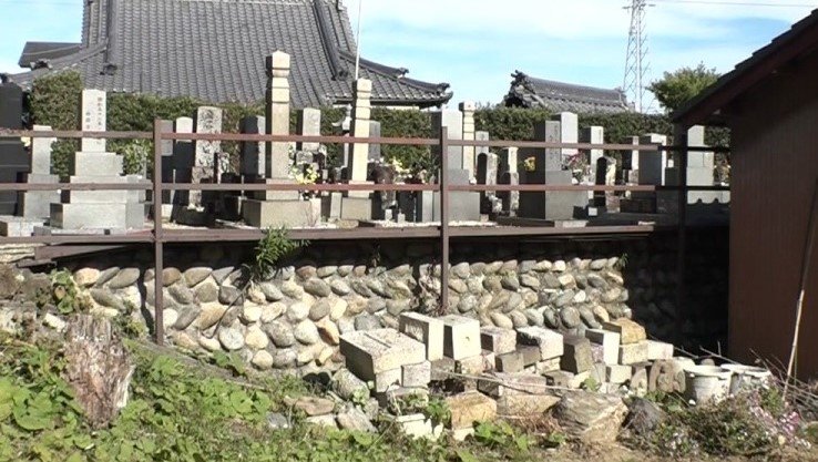 写真下部、積まれた「持ち主不明」の墓石