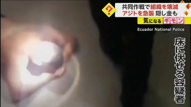 頭の後ろに手を回し、床に伏せる容疑者