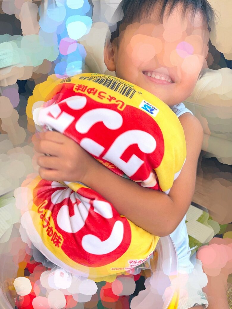 ワンタンクッションを抱きかかえてうれしそうな息子さん
