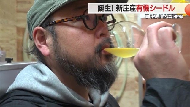 きれいな琥珀色のシードルを試飲するリンゴリらっぱ醸造所代表・佐藤春樹さん