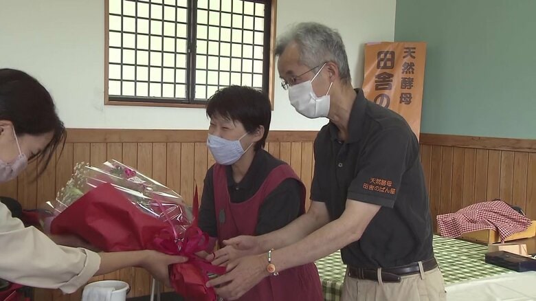 地元の人から花束を受け取る松崎さん夫妻