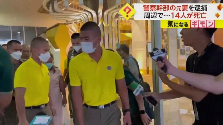 警察に周りを囲まれながら歩く、ピンク色の服の女