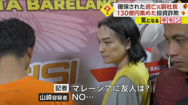 記者からの質問に回答する山崎容疑者