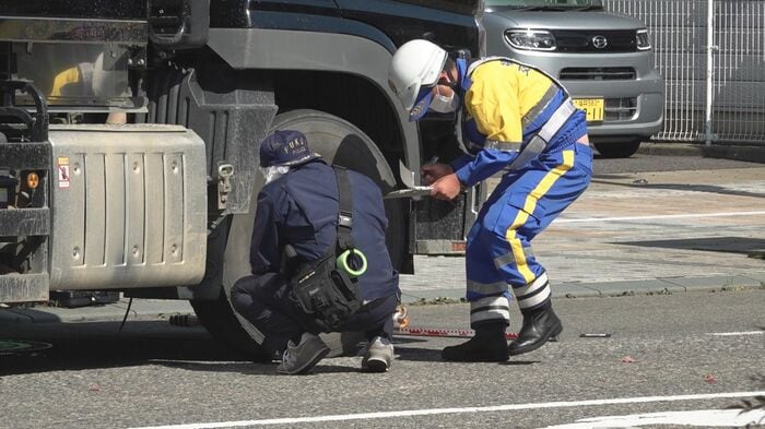 歩行者をはねた大型ダンプの後輪付近を調べる捜査員（1日午後1時頃撮影）