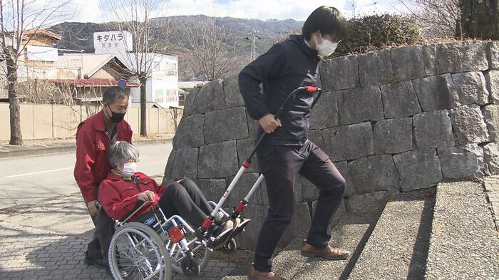 スタッフが乗った車イスを引く記者 長野県箕輪町