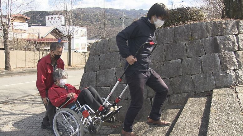 スタッフが乗った車イスを引く記者　長野県箕輪町