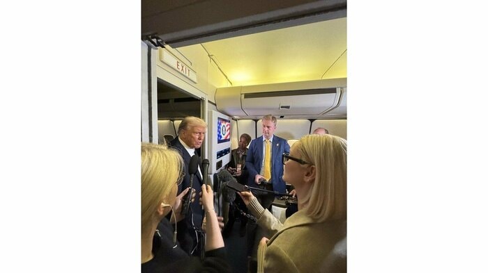 大統領専用機内で記者団の質問に応じるトランプ大統領