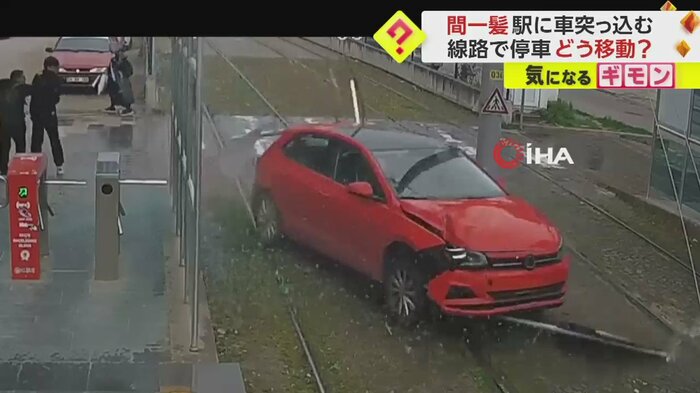 壁を破壊しながら線路へ入っていく赤い車