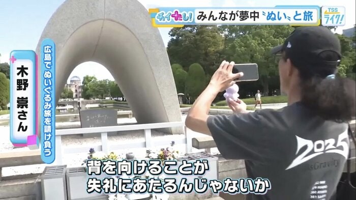 預かったぬいぐるみを慰霊碑の前で撮影