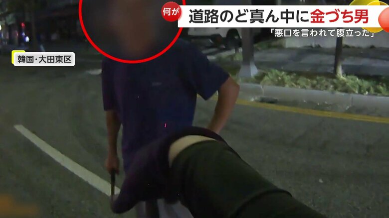 片側３車線の道路の真ん中で、金づちを持って通行を邪魔する男