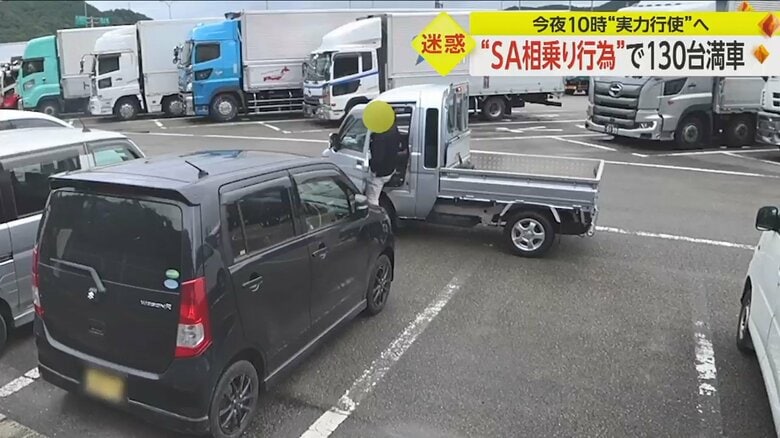 黒い車から出てきた人が軽トラックに乗車