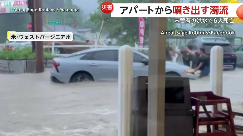 膝のあたりまで浸かりながら車を押す住民