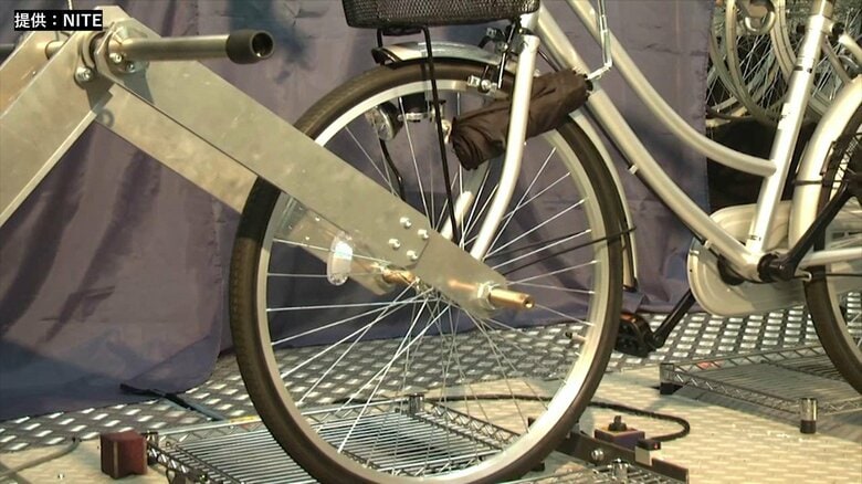 ハンドルにぶら下げた折りたたみ傘が、タイヤに挟まった事を想定した実験。傘の柄が大きく折れ曲がるほど、強い力で引き込まれた事が分かる（提供：NITE）