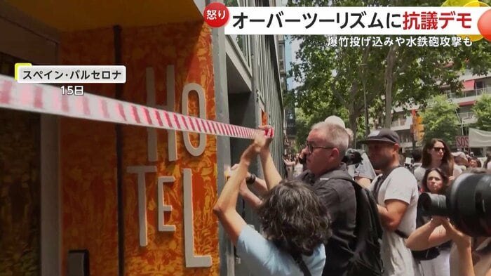 テープでホテルの入り口をふさごうとするデモ参加者たち