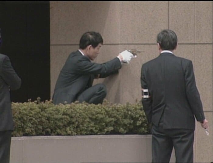 銃撃犯役の警察官が狙撃現場で銃を構える