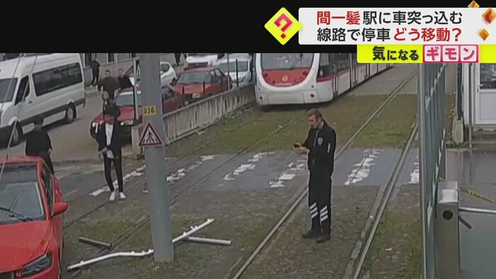 赤い車を前に停止する電車(IHA)