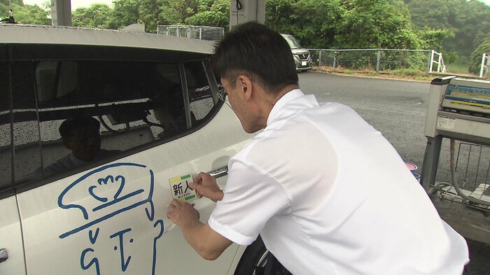 車両に新人マークを貼る初村さん