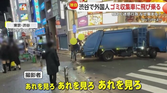 ゴミ収集車によじ登ろうとする外国人2人組