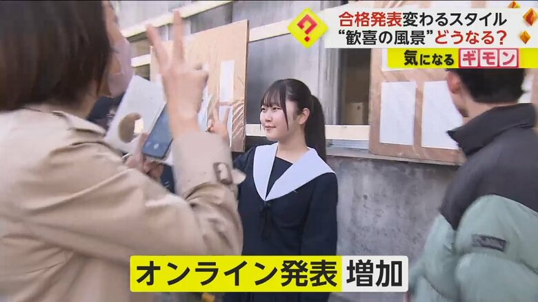 掲示板の前に立ち、記念撮影をする生徒