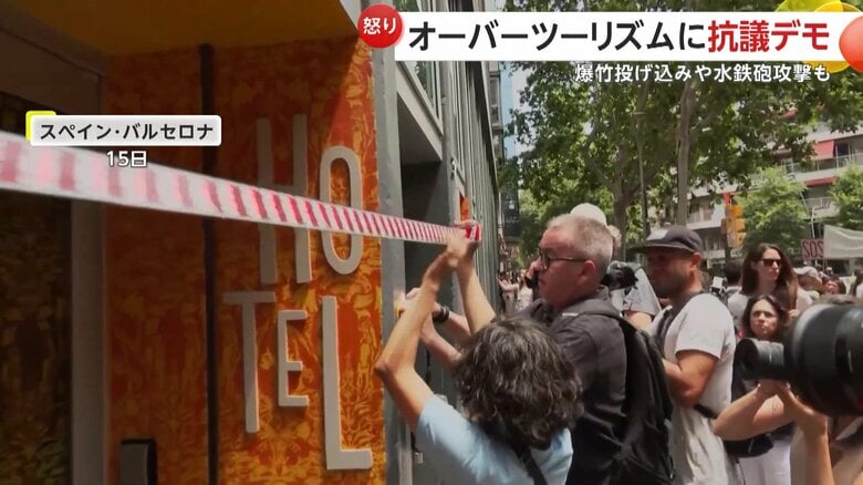 テープでホテルの入り口をふさごうとするデモ参加者たち