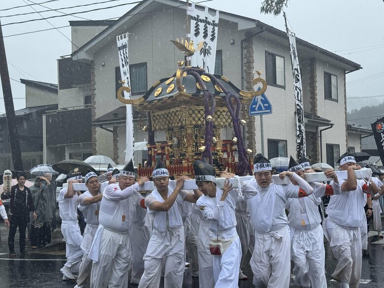 雨の中、大きな神輿が街中を練り歩いた