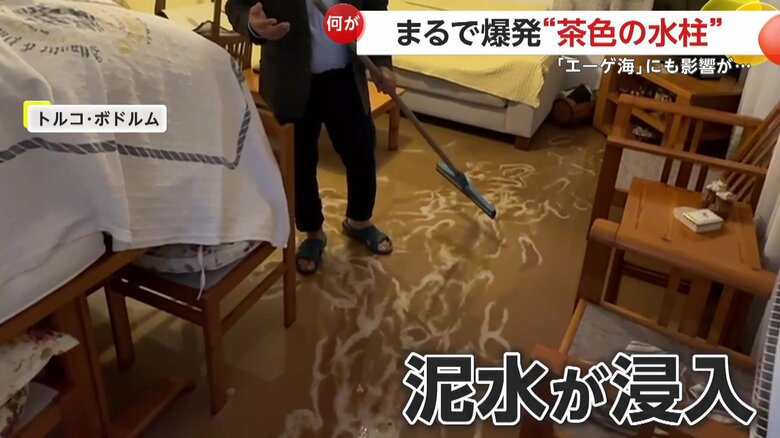 浸水した住宅の床を掃除し続ける男性（IHA）