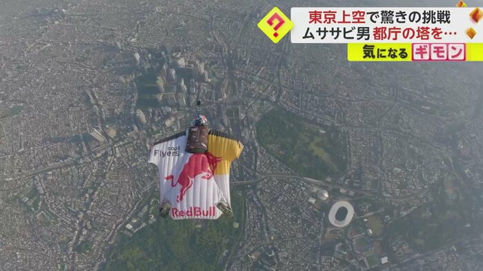 東京上空を滑空するように飛ぶ、ウィングスーツを身にまとった男性