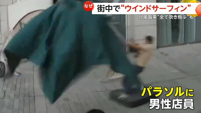 飛ばされるパラソルに必死にしがみつく男性店員(中国SNS)