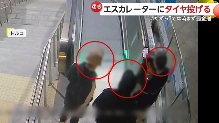 落としたゴミ袋とタイヤを撮影しながら喜ぶ3人組